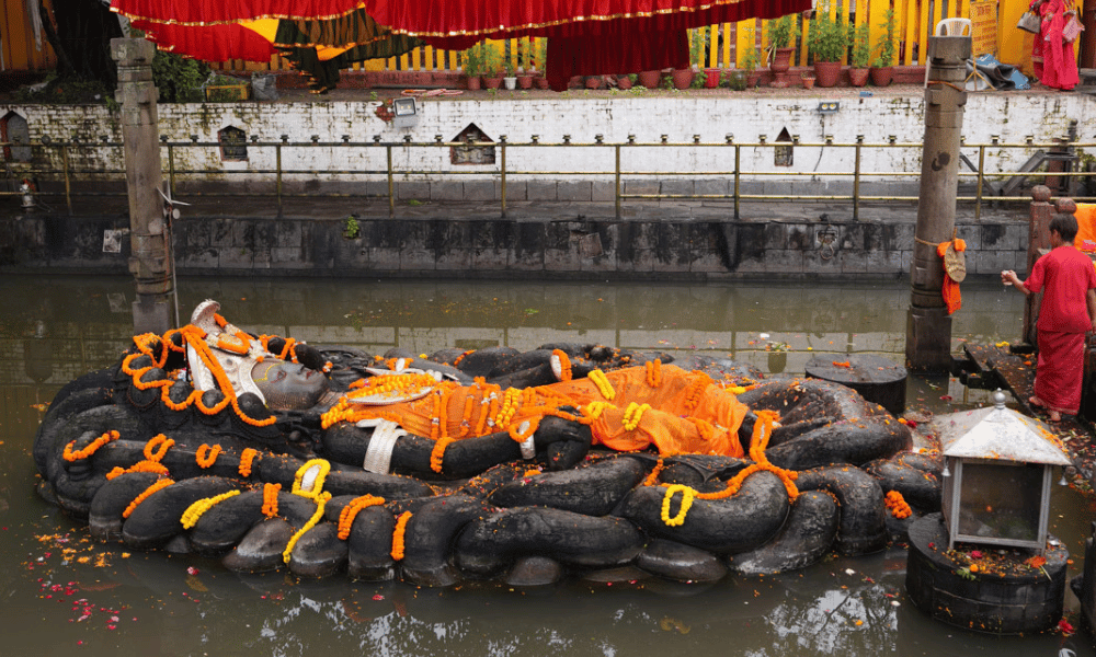 Budhanilkantha Temple in Kathmandu, Nepal, featuring the large reclining statue of Lord Vishnu lying on a bed of cosmic serpents in a sacred pond, surrounded by devotees and peaceful surroundings.